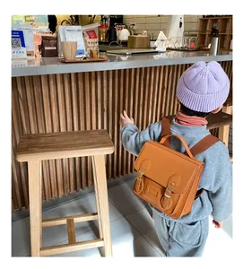Rear view of child wearing vintage brown PU leather satchel backpack in a cafe setting