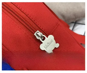 Close-up of cute bear-shaped metal zipper head on a lightweight red toddler backpack