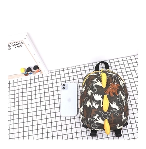 Détail d'un sac à dos dinosaure mignon avec ailerons 3D jaunes et imprimé camouflage