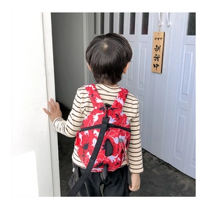 Detail of red dinosaur print kids backpack with a black safety anti-lost leash