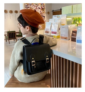 Close-up of a vintage black PU leather kids backpack in a cozy cafe setting