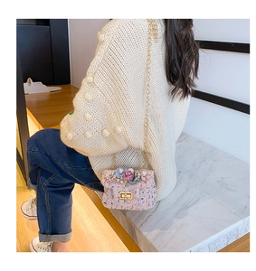 Détail d'un mini sac bandoulière en tweed avec fleurs sur l'épaule d'un enfant