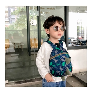 Detailed view of kids dinosaur backpack with 3D green fins and navy blue cartoon patterns