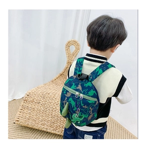 Détail du sac à dos dinosaure bleu marine avec pointes 3D porté par un jeune enfant