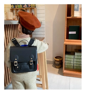 Detail view of black PU leather children backpack with magnetic buckles and adjustable straps