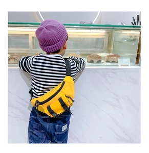 Detail of a bright yellow children's nylon chest bag with adjustable black straps and buckle