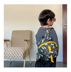 Boy's green camouflage dinosaur backpack with bright yellow accents on a child's back