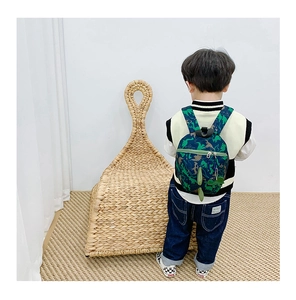Détail du motif dinosaure et queue 3D sur le sac à dos vert pour enfants