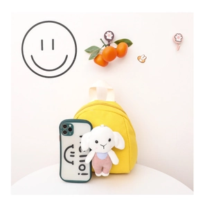 Detail of yellow canvas kids backpack with a cute white sheep plush toy charm accessory