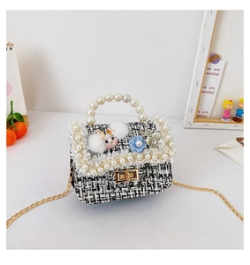 Detail of tweed mini bag with pearl handle, plush bunny charm and blue floral accent