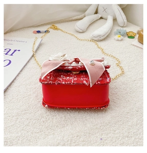 Close-up of red tweed girl bag with pearl flowers, ribbon bow and gold chain strap