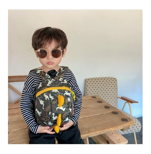 Toddler wearing a dinosaur backpack with 3D yellow fins and camouflage print details