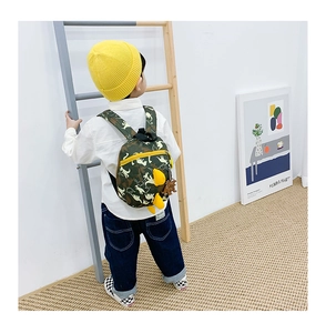 Détail du sac à dos camouflage pour enfant avec nageoires de dinosaure et breloque jaune