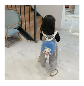 Blue toddler backpack with plush rabbit doll shown on a girl in a modern indoor setting