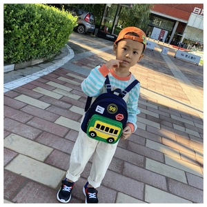 Detailed view of child wearing cartoon school bus backpack with yellow pocket and traffic icons
