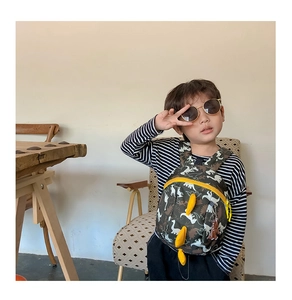 Toddler backpack with 3D yellow dinosaur plates and adjustable straps on a child