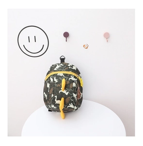 Detail of cartoon dinosaur backpack featuring 3D yellow fins and olive green canvas print