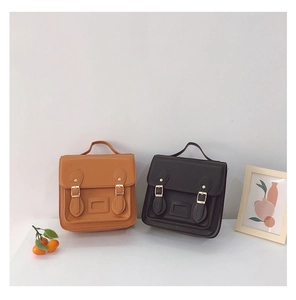 Close-up of vintage PU leather satchel bags in brown and black with metal buckles