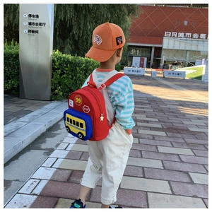 Outdoor view of children's cartoon red bus backpack showing straps and fit on a toddler