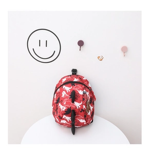 Detail of red toddler dinosaur backpack with anti-lost strap and cartoon pattern