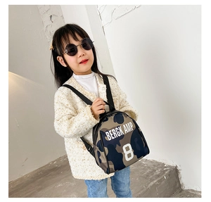 Detailed close-up of child's camouflage backpack with letter prints on adjustable straps