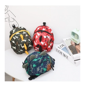 Detailed view of kids dinosaur backpacks in army green red and navy blue on a white table