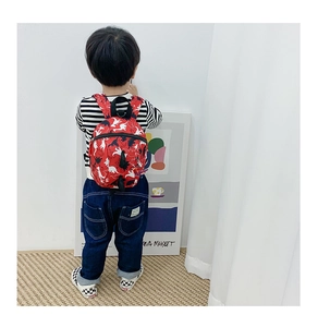 Détail d'un sac à dos enfant rouge avec imprimés dinosaures et tissu en toile