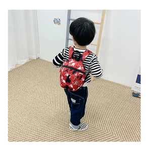 Détail du sac à dos rouge pour enfant avec motif dinosaure porté par un enfant