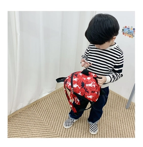 Détail d'un sac à dos rouge pour enfant avec motif dinosaure et bretelles réglables