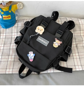 Détail d'un sac à dos noir en nylon avec boucles réglables et trois badges de dessin animé