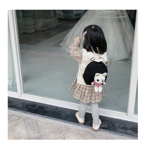 Rear view of a child wearing a black canvas backpack with a cute plush bear detail
