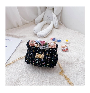 Détail du sac bandoulière en tweed pour enfant avec fleurs et perles sur fond en peluche