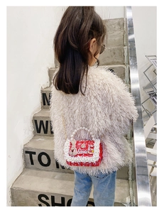 Close-up of red tweed girl's bag with pearl handle, love lettering and rabbit charm