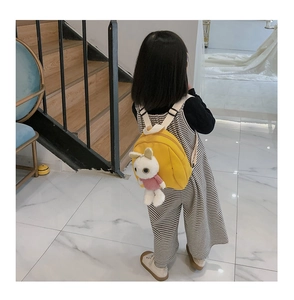 Detail of yellow toddler backpack with a cute white rabbit plush doll on the back
