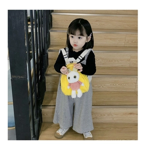 Detail of yellow canvas kids backpack with a cute white plush bunny and adjustable straps