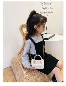 Detail of girls' woven crossbody bag with pearl handle and cute 3D cartoon charms