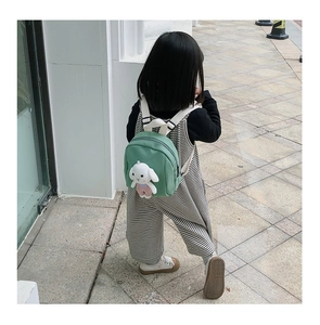 Detail view of a green mini toddler backpack with a cute plush bunny doll on the back