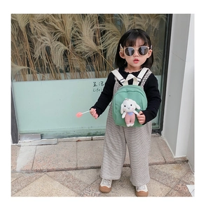 Close-up of green canvas toddler backpack featuring a cute plush bunny and woven straps