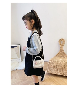 Girl's white tweed handbag with pearl handle and metal chain shown on a child model
