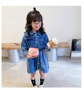 Petite fille en robe en denim avec un sac à bandoulière rose en forme de cœur marbré