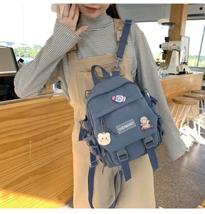 Détail du sac à dos en nylon bleu avec épinglettes de dessins animés au café