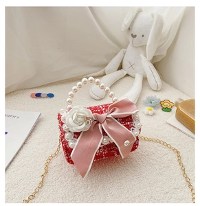 Detail of red tweed girl's handbag with pearl handle, lace trim, and camellia bow
