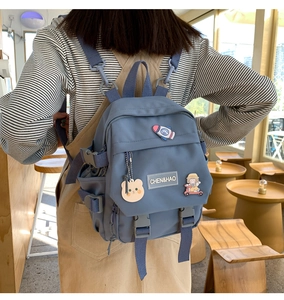 Détail d'un sac à dos bleu gris de style coréen avec badges et porte-clés ourson