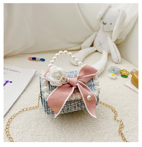 Close-up of blue tweed mini bag featuring a pink satin bow and pearl handle detail