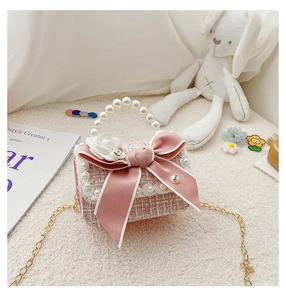 Detail of pink tweed girl's bag with pearl handle, ribbon bow, and white rose flower