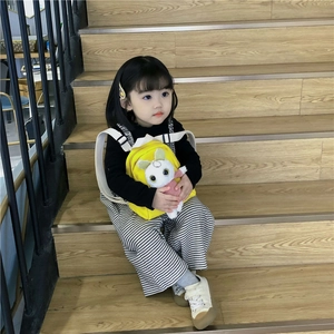 Cute yellow toddler backpack with 3D plush bunny doll on wooden stairs back view