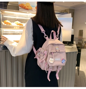 Détail d'un sac à dos rose en toile avec badges astronaute et pendentif ours mignon