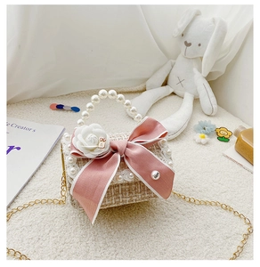 Close-up of girls' tweed mini handbag with pearls, pink bow and white camellia flower