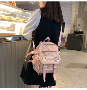 Détail d'un sac à dos rose en nylon pour étudiantes avec badges de dessins animés mignons