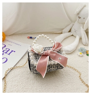 Close-up of tweed mini bag with pink satin bow, camellia flower and pearl handle
